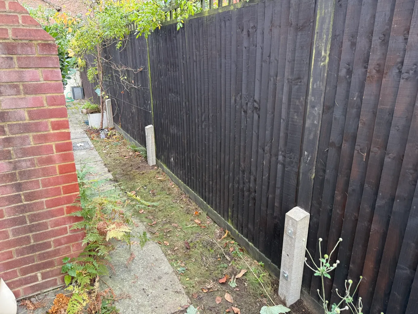 Damaged fence panel being repaired on a garden boundary