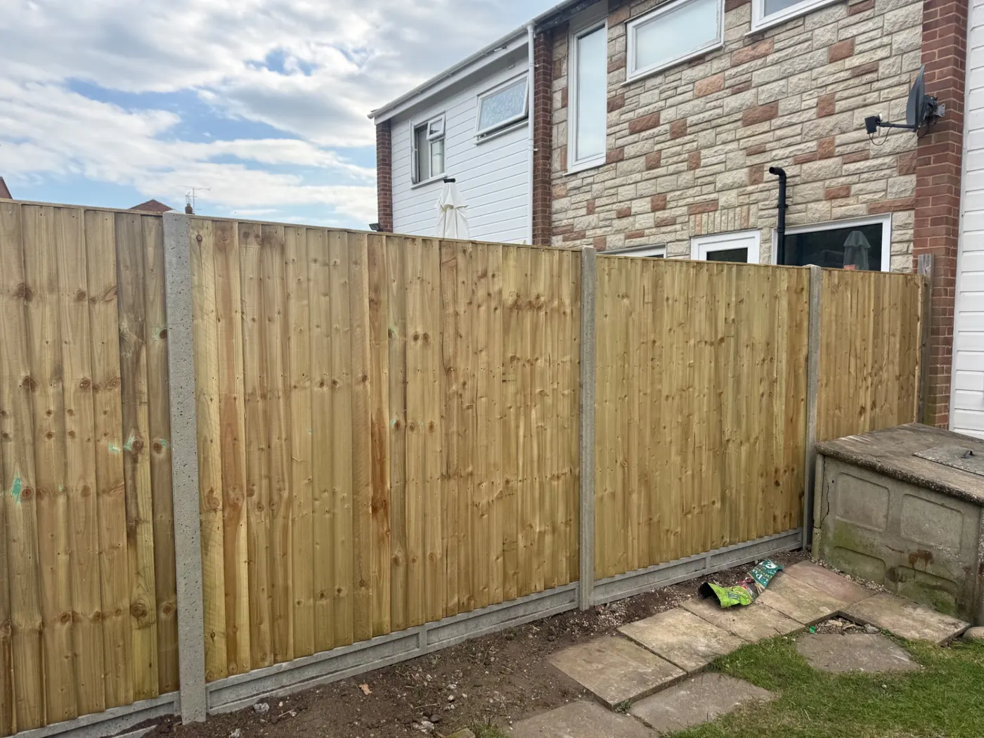 New feather edge fence panels with concrete posts behind a house