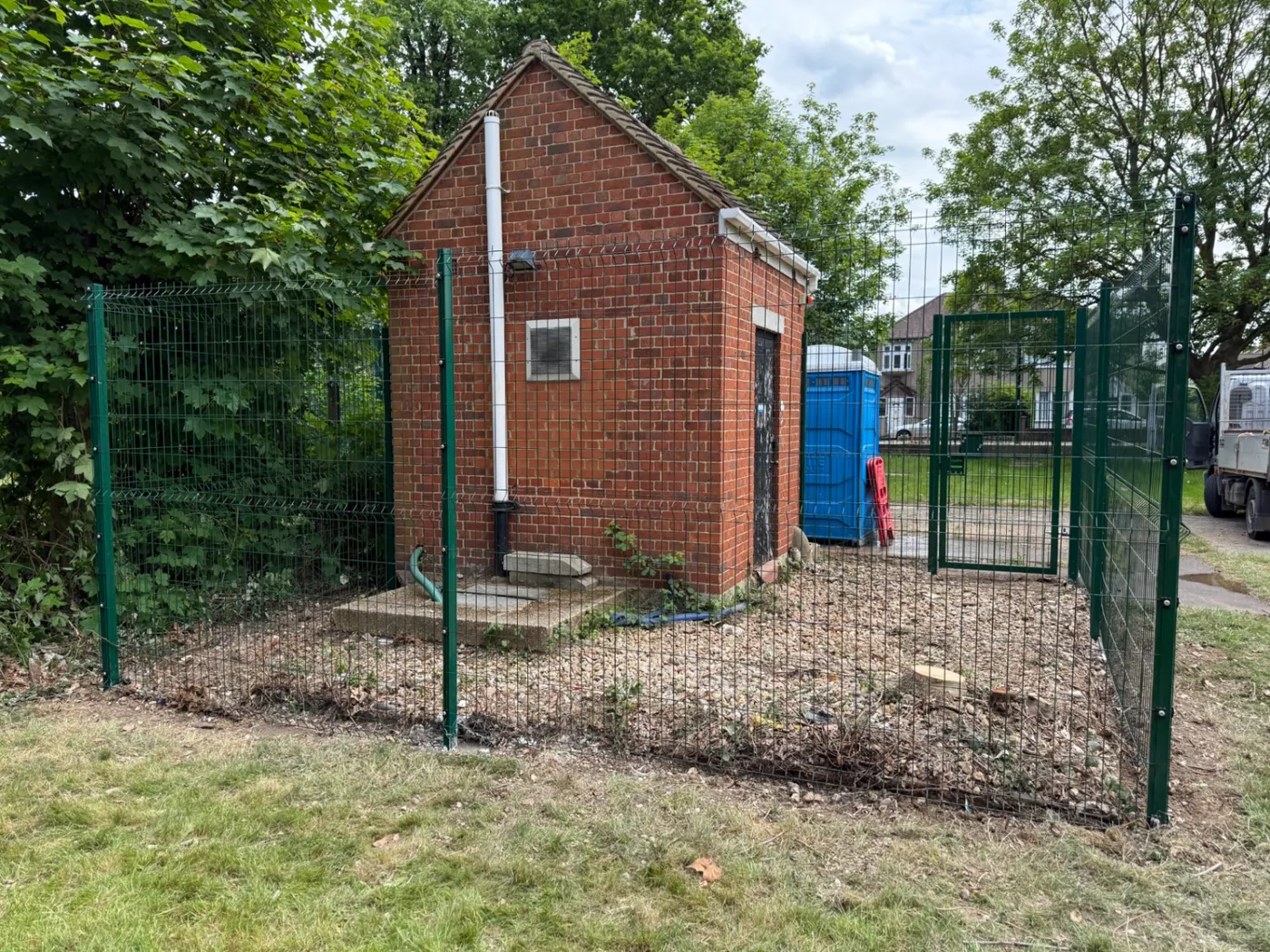 Green mesh security fencing and gate around a utility building