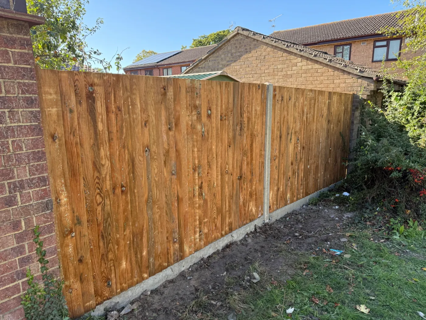 Closeboard fence built up to a brick wall with concrete posts