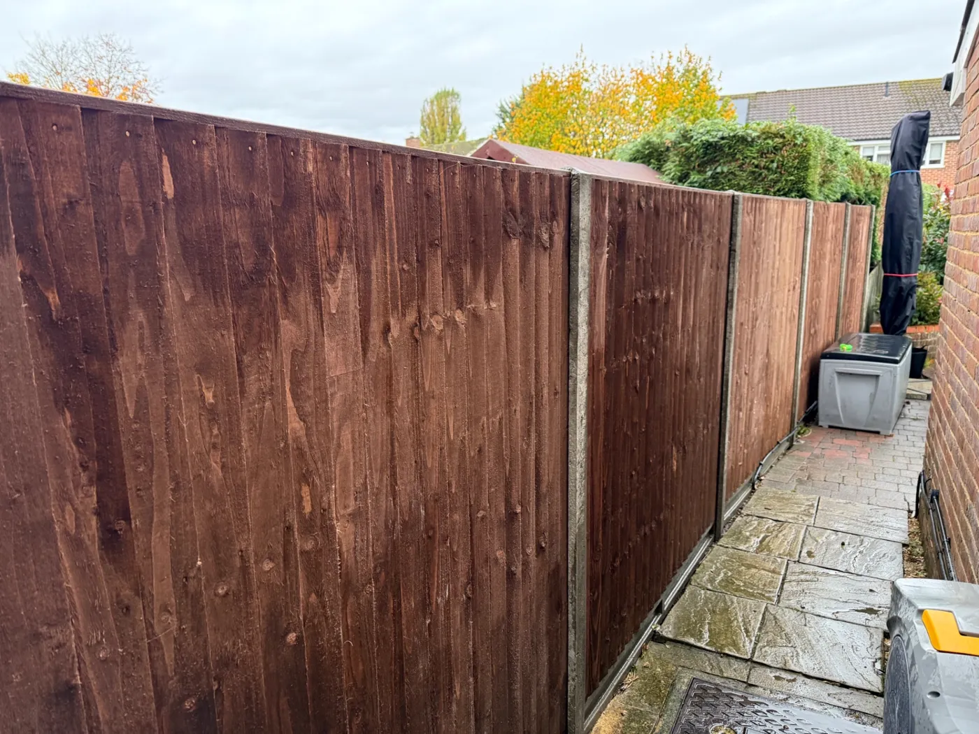 New dark stained fence panels installed along a narrow side passage