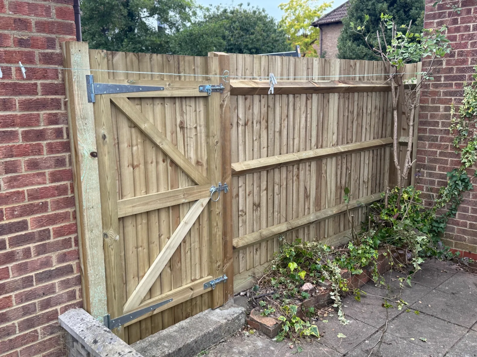 Braced feather edge garden gate hung next to a new closeboard fence