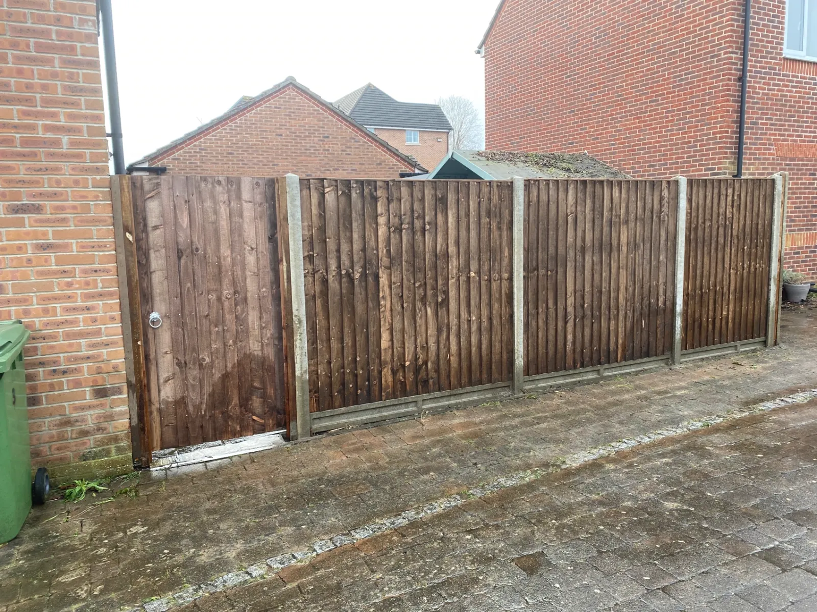 Closeboard side gate matching a brown stained fence run along a driveway